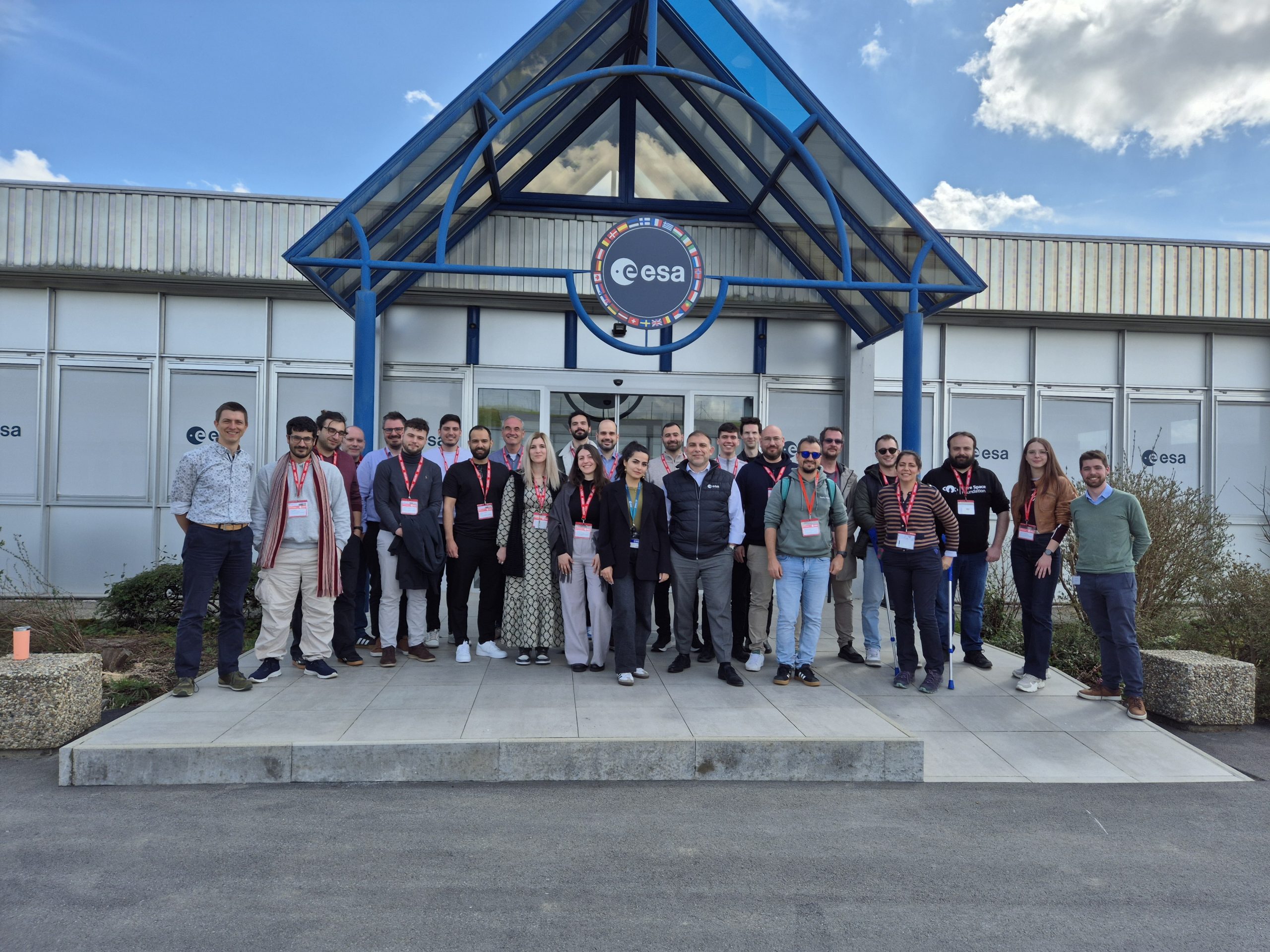 Group of people outside a building. The sky is blue.